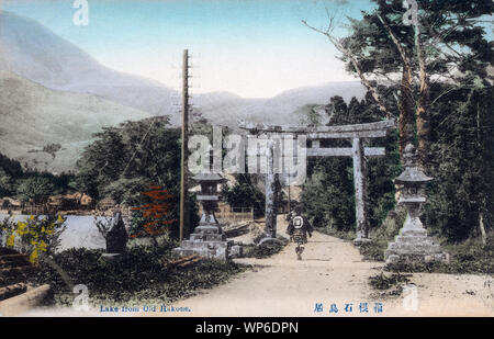 [1900s Japan - Heilige Torii-tor in Hakone] - zwei steinlaternen vor dem Ichino torii (一の鳥居), eine heilige Tor am Eingang von Hakone Jinja (箱根神社), ein Shinto Schrein in Hakone, der Präfektur Kanagawa. Teil der See Ashinoko gesehen werden kann. 20. jahrhundert alte Ansichtskarte. Stockfoto