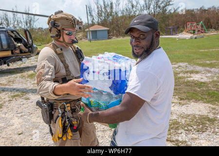 Fox Town, Abaco, Bahamas. 06. September 2019. Us-amerikanischen Zoll- und Grenzschutzbehörden Offiziere arbeiten mit lokalen Beamten, Wasser und Verbrauchsmaterialien für die Überlebenden in der Nachmahd des Hurrikans Dorian September 6, 2019 im Fox Town, Abaco, Bahamas zu entladen. Dorian schlug die kleine Insel Nation als Kategorie 5 Sturm mit Windgeschwindigkeiten von 185 km/h. Stockfoto