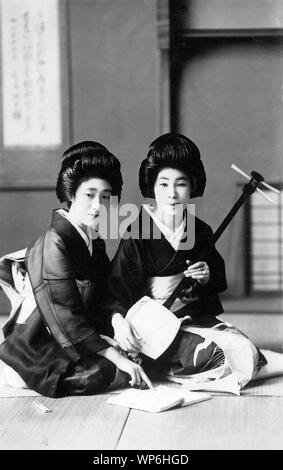 [1920s Japan - Japanische Geisha üben die Shamisen] - Geisha Üben der Shamisen. 20. jahrhundert alte Ansichtskarte. Stockfoto