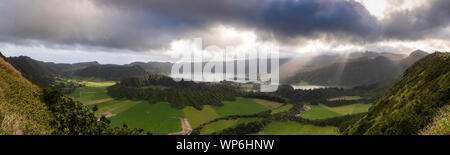 Landschaft Panorama mit Sonnenlicht Strahlen durch die Wolken über den beeindruckenden vulkanischen Krater Sete Cidades, Insel Sao Miguel, Azoren glänzen. Uhr Stockfoto