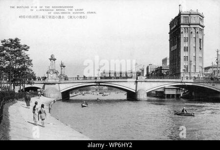 [1920s Japan - Naniwabashi Brücke in Osaka] - Naniwabashi Brücke überspannt den Alten Yodo Fluss und wurde 1915 abgeschlossen. Die Brücke wurde für seine Strassenlaternen und Statuen von Löwen bekannt. Es kennzeichnete beeindruckende Steintreppe führt zu Nakanoshima Island und die Waterfront Park, die im Bau war zu der Zeit die Brücke gebaut wurde. Sie steht noch und ist eine der ältesten Brücken im westlichen Stil in Japan. 20. jahrhundert alte Ansichtskarte. Stockfoto