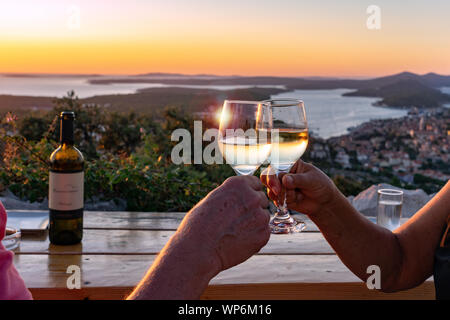 Einen Toast mit Wein über einen malerischen Blick auf die kroatischen Inseln in der Kvarner Bucht bei Sonnenuntergang Stockfoto