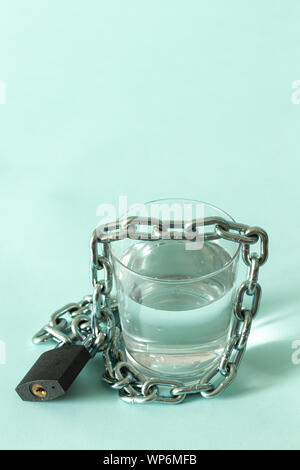 Ein Glas Wasser in einer Kette gewickelt und mit einem Vorhängeschloss. Das Konzept des Problem der kleinen Trinkwasser in der Welt. Für t Ort Stockfoto