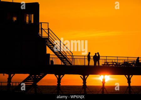 Aberystwyth Wales UK, Samstag, 07. September 2019 UK Wetter: die Menschen sind von der schönen Anfang Herbst Sonnenuntergang über Pier Aberystwyth, Wales UK silhouetted, am Ende eines Tages des klaren Himmel und warmen Sonnenschein, ein kalter Nordwind Brise gemildert. Foto Keith Morris/Alamy leben Nachrichten Stockfoto