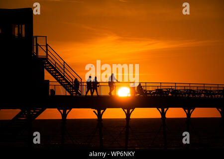 Aberystwyth Wales UK, Samstag, 07. September 2019 UK Wetter: die Menschen sind von der schönen Anfang Herbst Sonnenuntergang über Pier Aberystwyth, Wales UK silhouetted, am Ende eines Tages des klaren Himmel und warmen Sonnenschein, ein kalter Nordwind Brise gemildert. Foto Keith Morris/Alamy leben Nachrichten Stockfoto