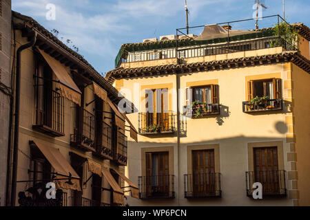 Zwei Gebäude, ein stumpfes Gelb gestrichen, in der Innenstadt von Toledo, Spanien. Stockfoto