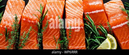 Lachs. Frischen, rohen Lachs Fisch Filet mit Zutaten zum Kochen, Kräuter und Zitrone auf schwarzen Hintergrund, Ansicht von oben, Banner Stockfoto