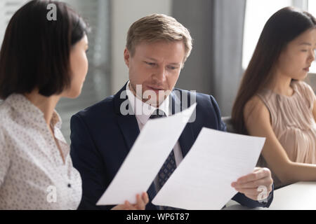 Schwere team leader Überprüfung Finanzbericht mit asiatischen weiblichen Kollegen. Stockfoto