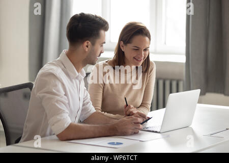 Glückliche Mitarbeiter diskutieren neue Unternehmen Software, Laptop. Stockfoto