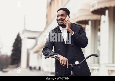 Schöner Mann am Telefon sprechen und das Fahren mit dem Fahrrad Stockfoto