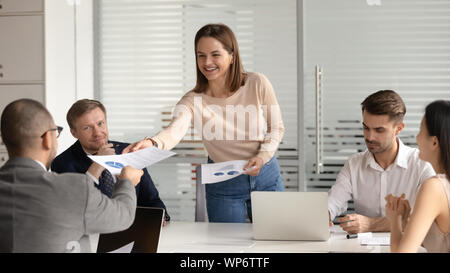 Lächelnd weibliche Moderatorin die Aushändigung von Dokumenten mit Diagrammen. Stockfoto