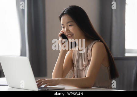 Glückliche junge asiatische Mitarbeiter diskutieren Projektdetails mit Firmenkunden. Stockfoto