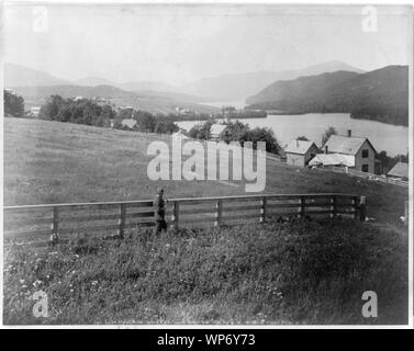 Lake Placid vom Grand View House, [Aidrondack Bergen, New York, mit einem Mann, der durch Zaun im Feld im Vordergrund] Stockfoto