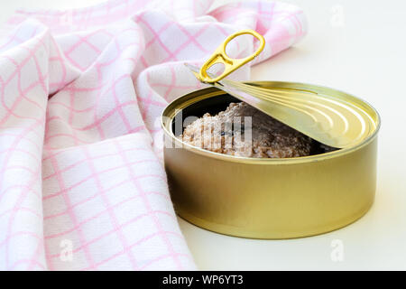 Fast gelb Runde Dose geöffnet kann mit Cod Kaviar in Öl in der Nähe karierten Küchenhandtuch auf einem weißen Tisch. Öffnen einer Essen kann mit Lasche ziehen. Close-up. Stockfoto