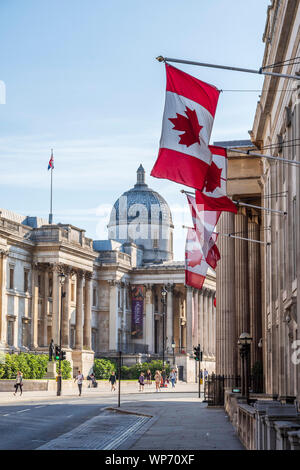 Kanadische Fahnen an den Kanada hohe Kommission Gebäude in London hängend, mit der Nationalen Galerie hinter Stockfoto