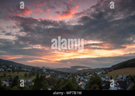 Panoramablick über die bergige Spa Village von Grafschaft im Winter Sport Region Sauerland, Deutschland, während ein farbenfroher Sonnenuntergang Stockfoto