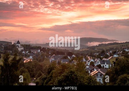 Panoramablick über die bergige Spa Village von Grafschaft im Winter Sport Region Sauerland, Deutschland, während ein farbenfroher Sonnenuntergang Stockfoto