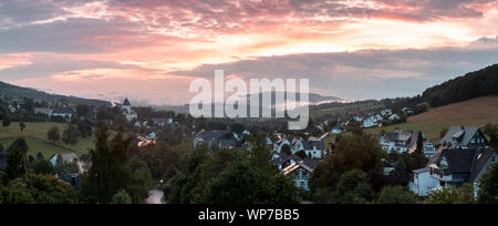 Weiten Panoramablick über die bergige Spa Village von Grafschaft im Winter Sport Region Sauerland, Deutschland, während ein farbenfroher Sonnenuntergang Stockfoto