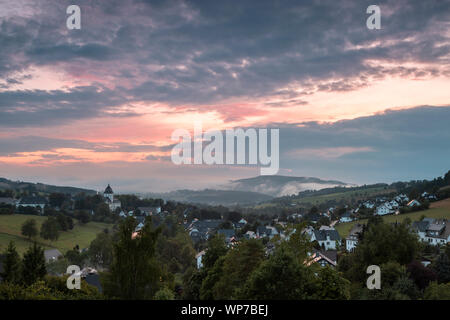 Panoramablick über die bergige Spa Village von Grafschaft im Winter Sport Region Sauerland, Deutschland, während ein farbenfroher Sonnenuntergang Stockfoto