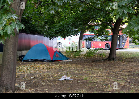 Zelt von Obdachlosen im öffentlichen Raum in London von Hyde Park, mit roten Bus im Hintergrund Stockfoto