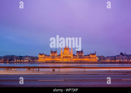 Stadtbild von Budapest mit bunten Parlament und Donau. Rosa und Lila Farben von Himmel und leichte Spuren von Autos. Stockfoto