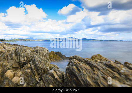 (Selektive Fokus) Schönen Meereslandschaft mit einem bewölkten Himmel, Türkis (silky) Wasser und einige Felsformationen im Vordergrund. Costa Smeralda, Sardinien. Stockfoto