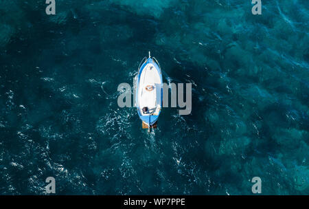 Ansicht von oben, einen atemberaubenden Blick auf einen wunderschönen Fischerboot mit einem Fischer an Bord Segeln auf blauem Meer. Küste von Amalfi, Italien. Stockfoto