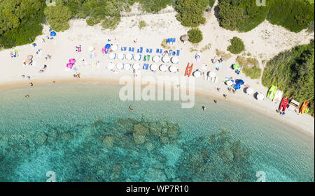 Ansicht von oben, einen atemberaubenden Blick auf einen wunderschönen Strand voll von bunten Sonnenschirmen und Menschen schwimmen im türkisblauen Wasser. Stockfoto