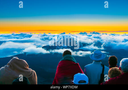 Sonnenaufgang über den Wolken und Berge in der Ferne von der Oberseite des Haleakala Kraters, Maui, Hawaii, USA Stockfoto