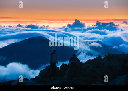 Leute, die Wolken bei Sonnenaufgang vom Gipfel des Haleakala Kraters auf Maui, Hawaii, USA Stockfoto