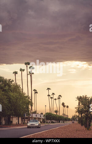 Analoge Fotografie von einem Cabrio fahren auf Peoria Avenue unter einem stürmischen Nachmittag Himmel in Sun City, Arizona. Stockfoto