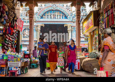 Madurai, Tamil Nadu/Indien - Januar 14, 2016: eine Indische Familie Spaziergänge durch einen Bogen von Geschäften belegt, mit berühmten Meenakshi Tempel hinter sich. Stockfoto