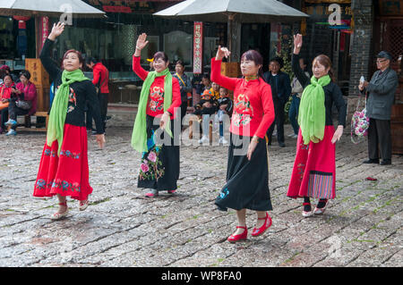 Weibliche folk Tänzer in einem Stadtplatz in der Altstadt von Lijiang, Yunnan, China Stockfoto