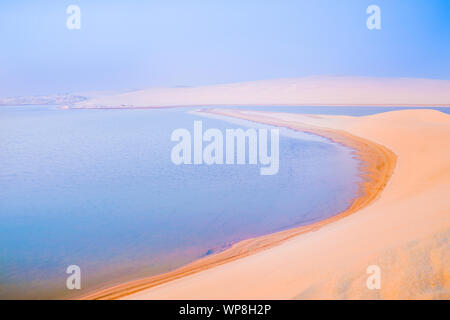 Wüste bei Sonnenaufgang, goldenen Farbton, bevor die Sonne über Sealine Dünen der Wüste und Binnensee mit seinen langen geschwungenen Strand. Stockfoto