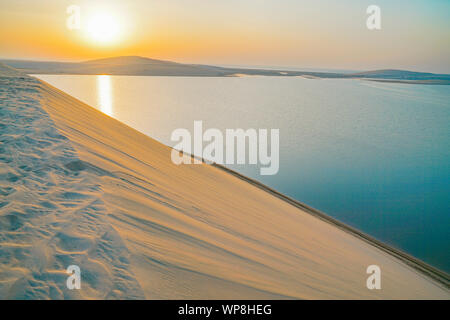 Wüste bei Sonnenaufgang, morgen Lichtschein über Dünen und Meer der Sealine Wüste gerade aus Doha, Katar. Stockfoto