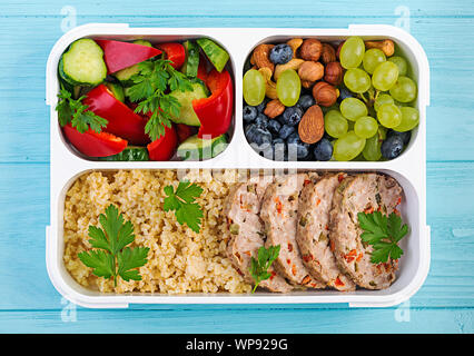 Lunch Box Hackbraten, Bulgur, Muttern, Gurke und Berry. Gesunde fitness Nahrung. Nehme. Brotdose. Ansicht von oben Stockfoto