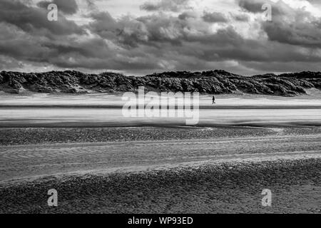 Einzelne Person allein gehen an einem windigen Strand von Bray-Dunes in Frankreich Stockfoto