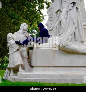 Junger Mann sitzt auf einem Denkmal für Ludovic Trarieux, zum Gedenken an die Gründung der Liga für Menschenrechte, Quadrat Claude-Nicolas Ledoux - Paris, FR. Stockfoto