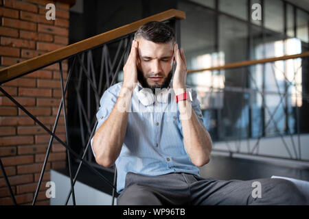 Der bärtige Mann, der Smart watch leiden unter Kopfschmerzen. Stockfoto