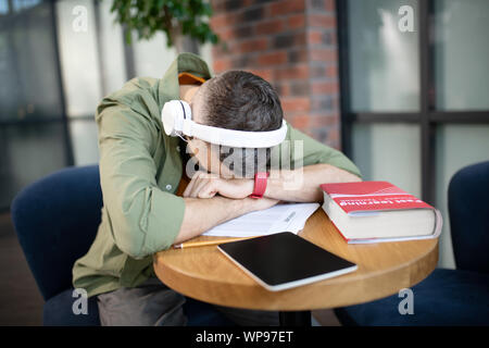 Student trägt Ohrhörer in ein Nickerchen nach dem Studium Stockfoto