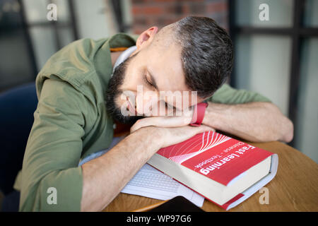 Dunkelhaarige student Schlafen nach dem Studium für zu lang. Stockfoto