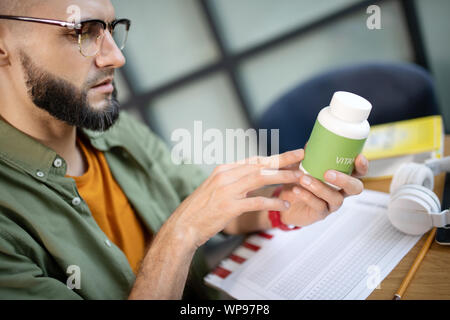 Bärtige stattlicher Mann in Gläsern lesen über Vitamine Stockfoto