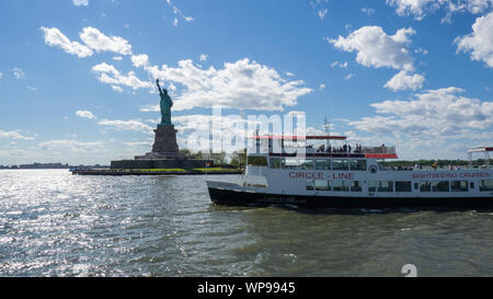 New York, USA. White Cruiser Boot vor der Freiheitsstatue. Sommer. Touristische Attraktion. Boot Köpfe zum Pier der Liberty Island Stockfoto