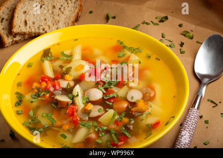 Suppe mit Gemüse, Wurst und Pasta in einem gelben Schild Stockfoto