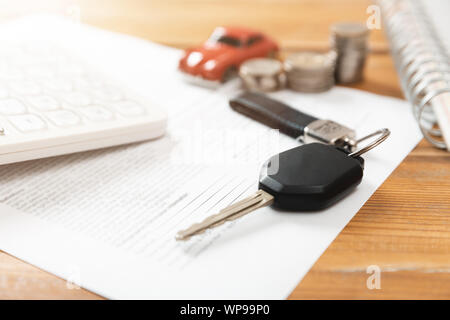 Auto kaufen Konzept. Autoschlüssel, Taschenrechner, Spielzeugauto, Münzen und Kaufvertrag Stockfoto