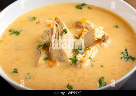 Ciorba radauteana - traditionelle rumänische Hühnersuppe mit Sahne und Knoblauch in einer weißen Schüssel Stockfoto
