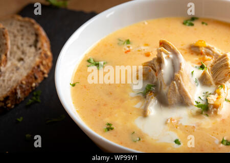 Ciorba radauteana - traditionelle rumänische Hühnersuppe mit Sahne und Knoblauch in einer weißen Schüssel Stockfoto