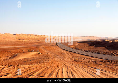 Wüste Straße und Dünen im Oman, Kamel durch die Straße, Wahiba Sands Stockfoto