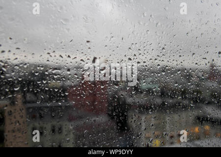 Regentropfen auf klare Glasscheibe, Reflexion des unscharfen Stadt und leichte Bokeh von Außen, schöne Farbe abstrakt, Hintergrund Stockfoto