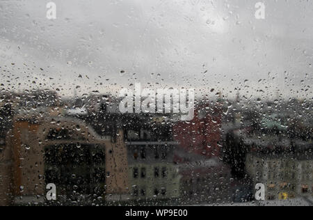 Regentropfen auf klare Glasscheibe, Reflexion des unscharfen Stadt und leichte Bokeh von Außen, schöne Farbe abstrakt, Hintergrund Stockfoto